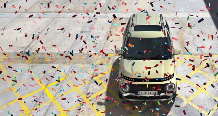 The new Hyundai INSTER in the colour beige. It stands on the right-hand side, confetti flies across the picture.