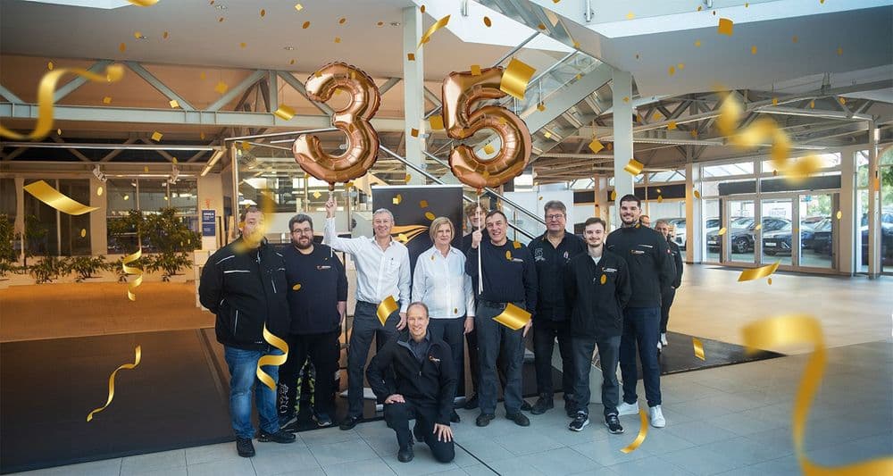 CSB Schimmel Automobile anniversary with balloons showing 35. 10 people standing in a car dealership.